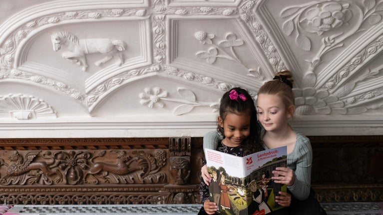 Visitors sat with a leaflet on scaffold enjoying the Long Gallery ceiling after conservation work at Lanhydrock, Cornwall